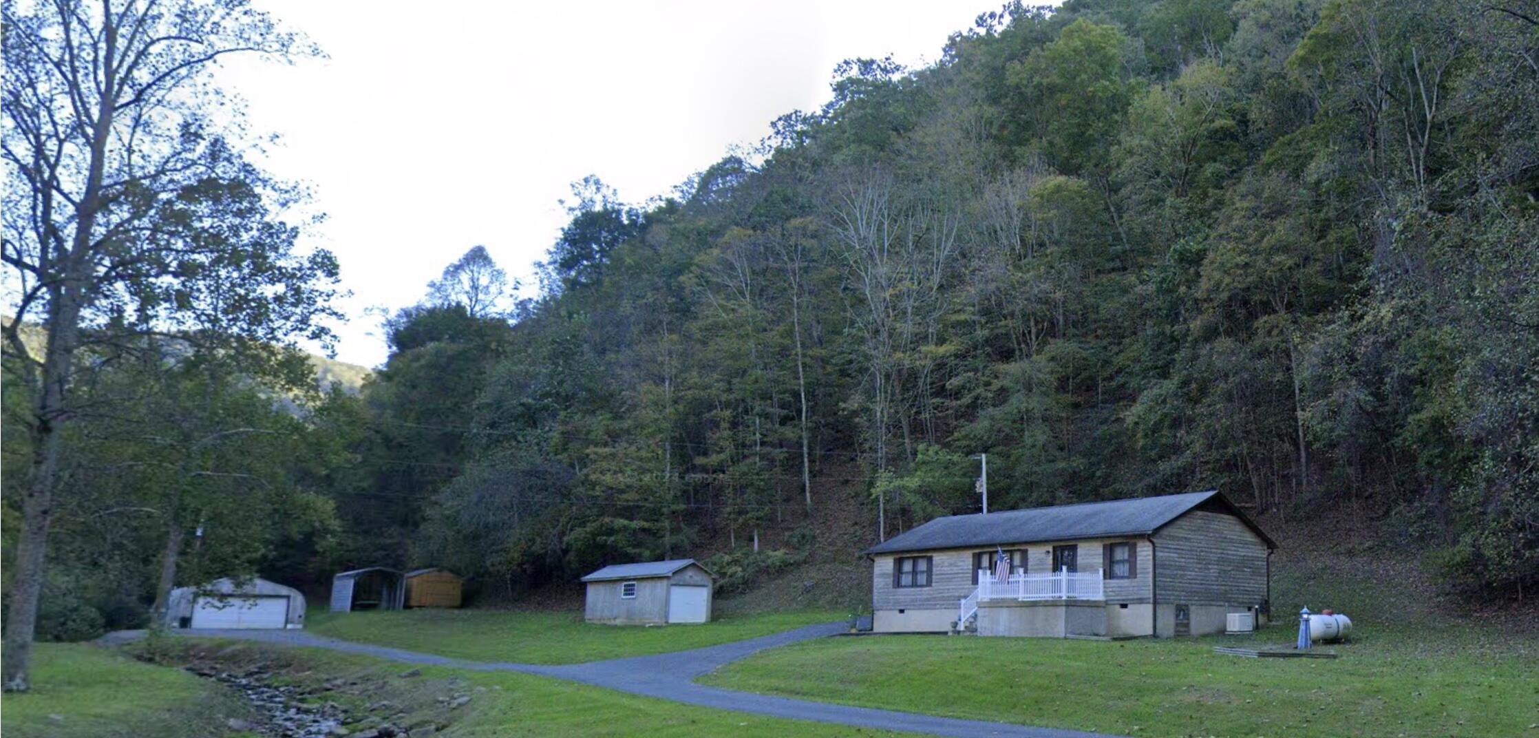 a view of a big house with a big yard and large trees