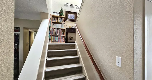 a view of staircase with lots of frames on wall and a window