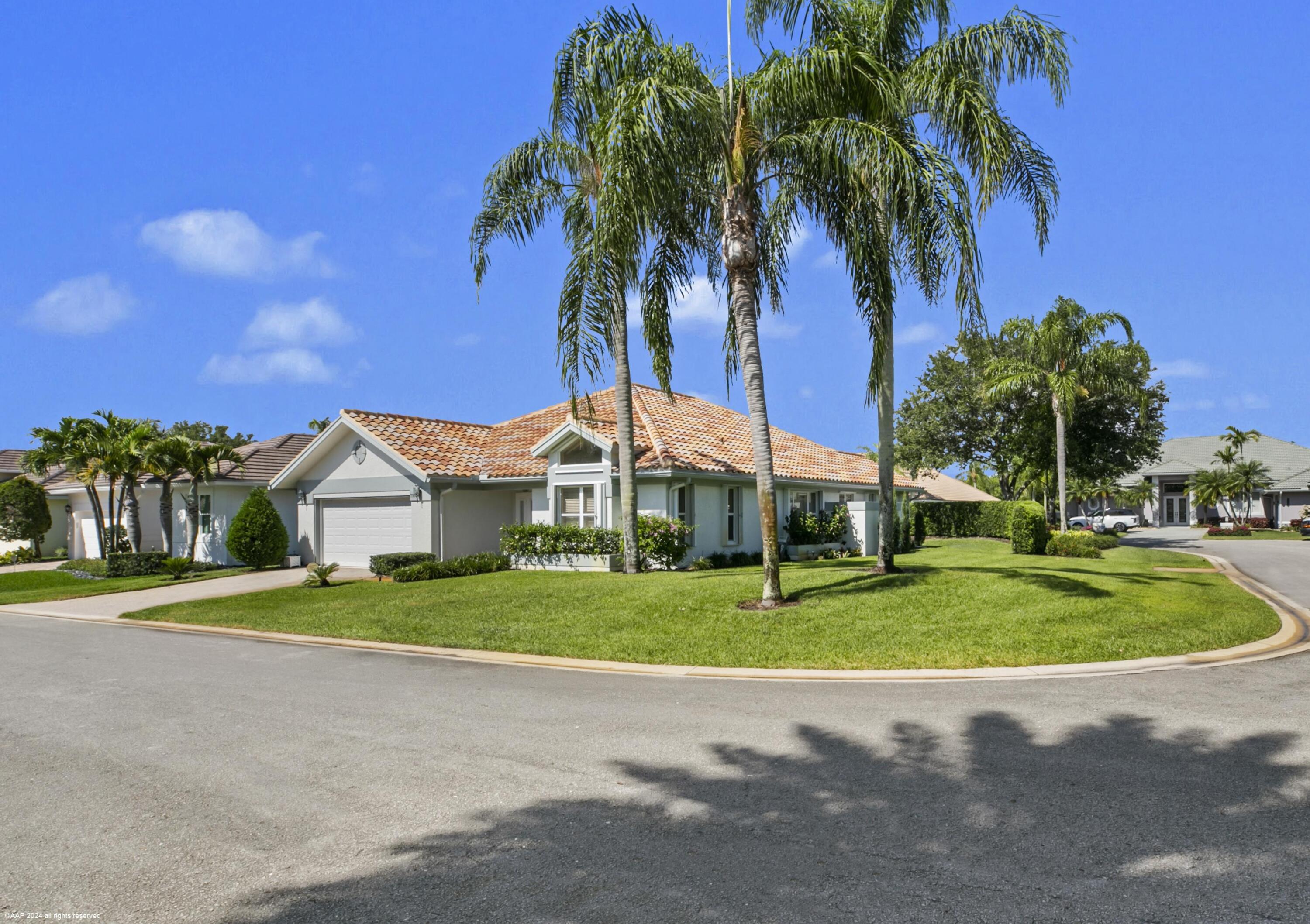 a front view of a house with a yard and palm trees
