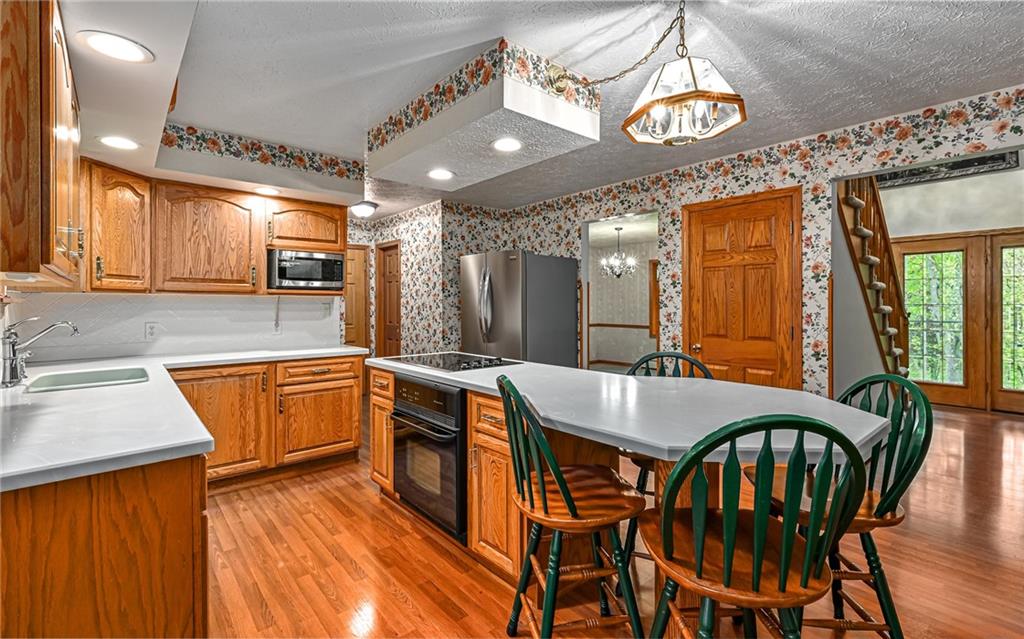 230 Election House Road Butler, PA 16001 - Photo 12 of 38 a kitchen with stainless steel appliances granite countertop a sink a stove a dining table and chairs with wooden floor