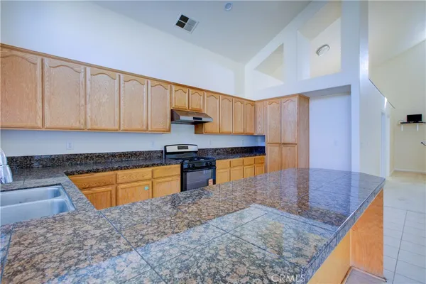 a kitchen with stainless steel appliances granite countertop a sink a stove top oven a counter space and cabinets