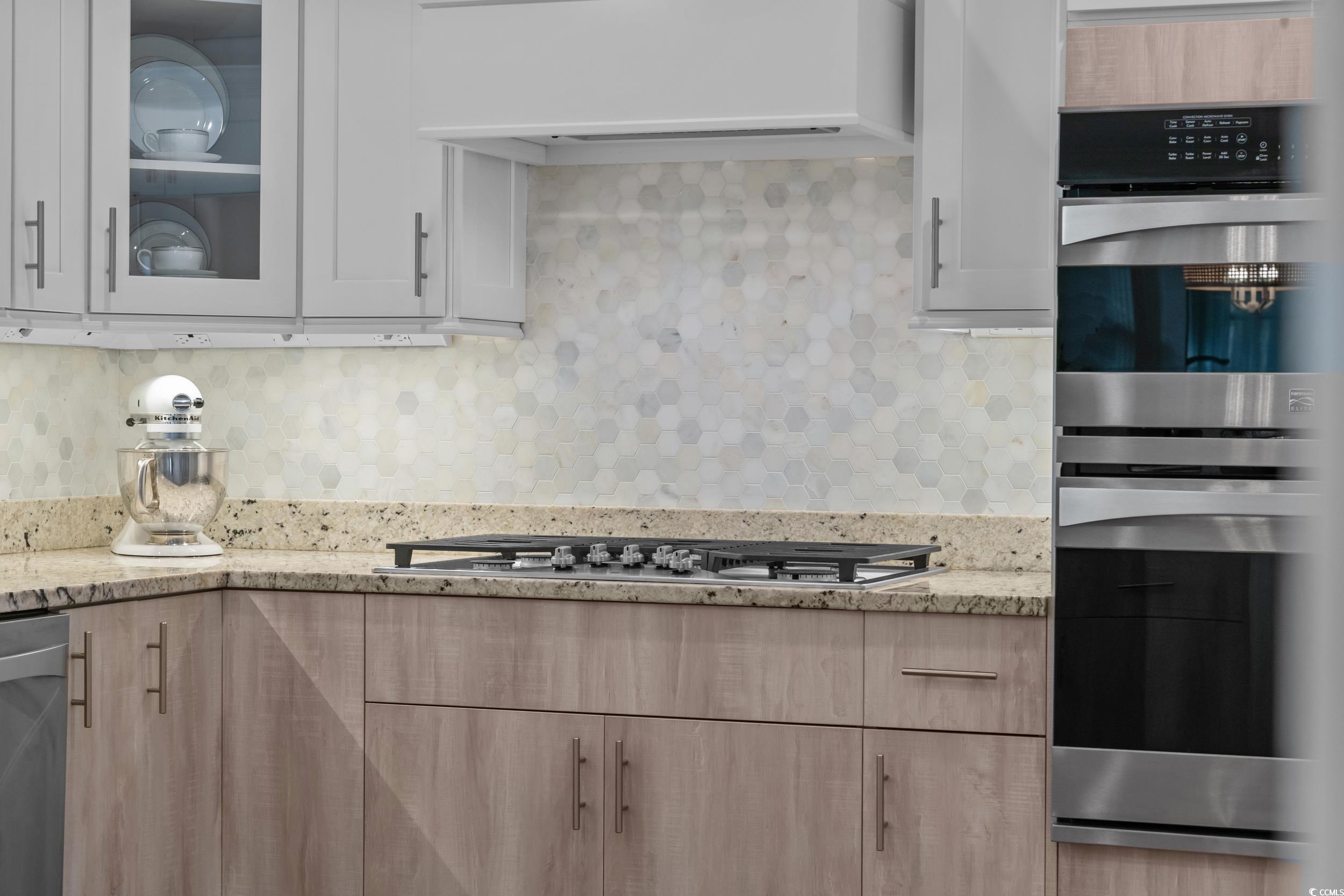 3021 Moss Bridge Lane Myrtle Beach, SC 29579 - Photo 14 of 40 Kitchen with appliances with stainless steel finishes, light stone countertops, premium range hood, decorative backsplash, and glass insert cabinets