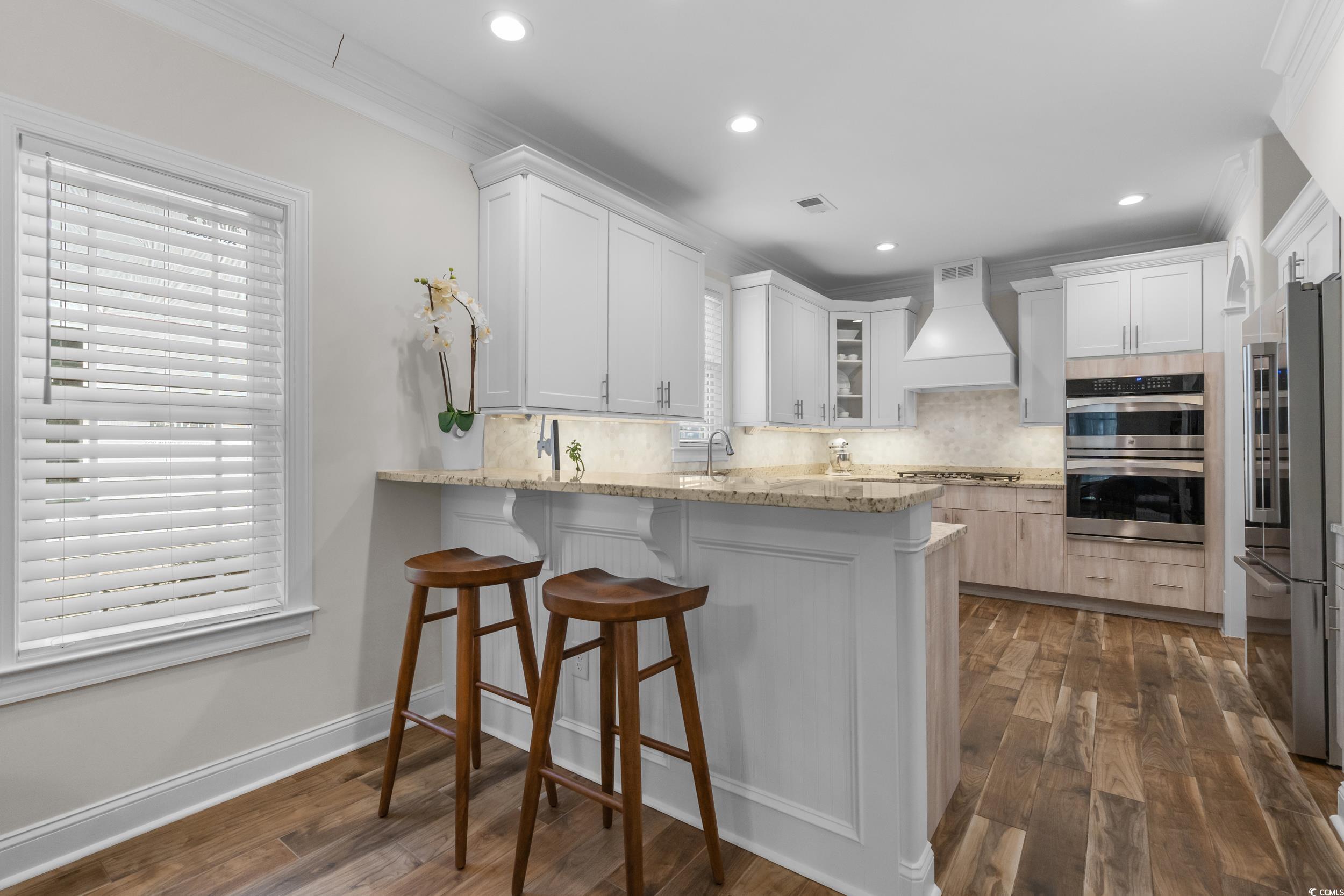3021 Moss Bridge Lane Myrtle Beach, SC 29579 - Photo 16 of 40 Kitchen with white cabinets, a breakfast bar, a peninsula, light stone counters, and backsplash