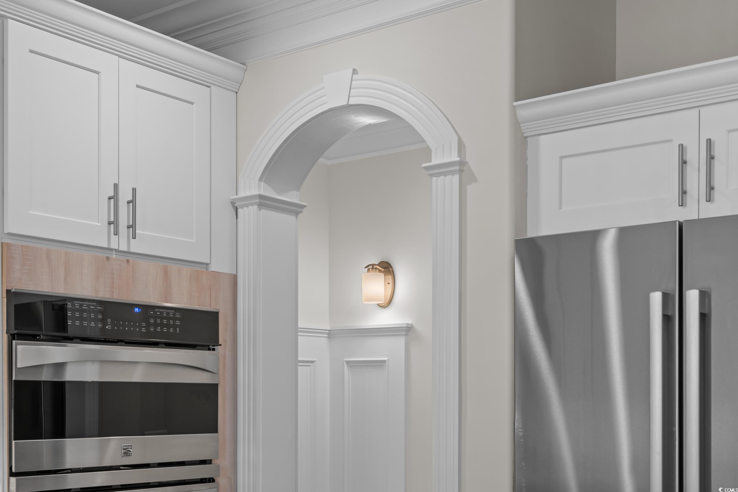 3021 Moss Bridge Lane Myrtle Beach, SC 29579 - Photo 18 of 40 Kitchen view of stainless steel appliances, crown molding, white cabinetry, arched walkways, and ornate columns