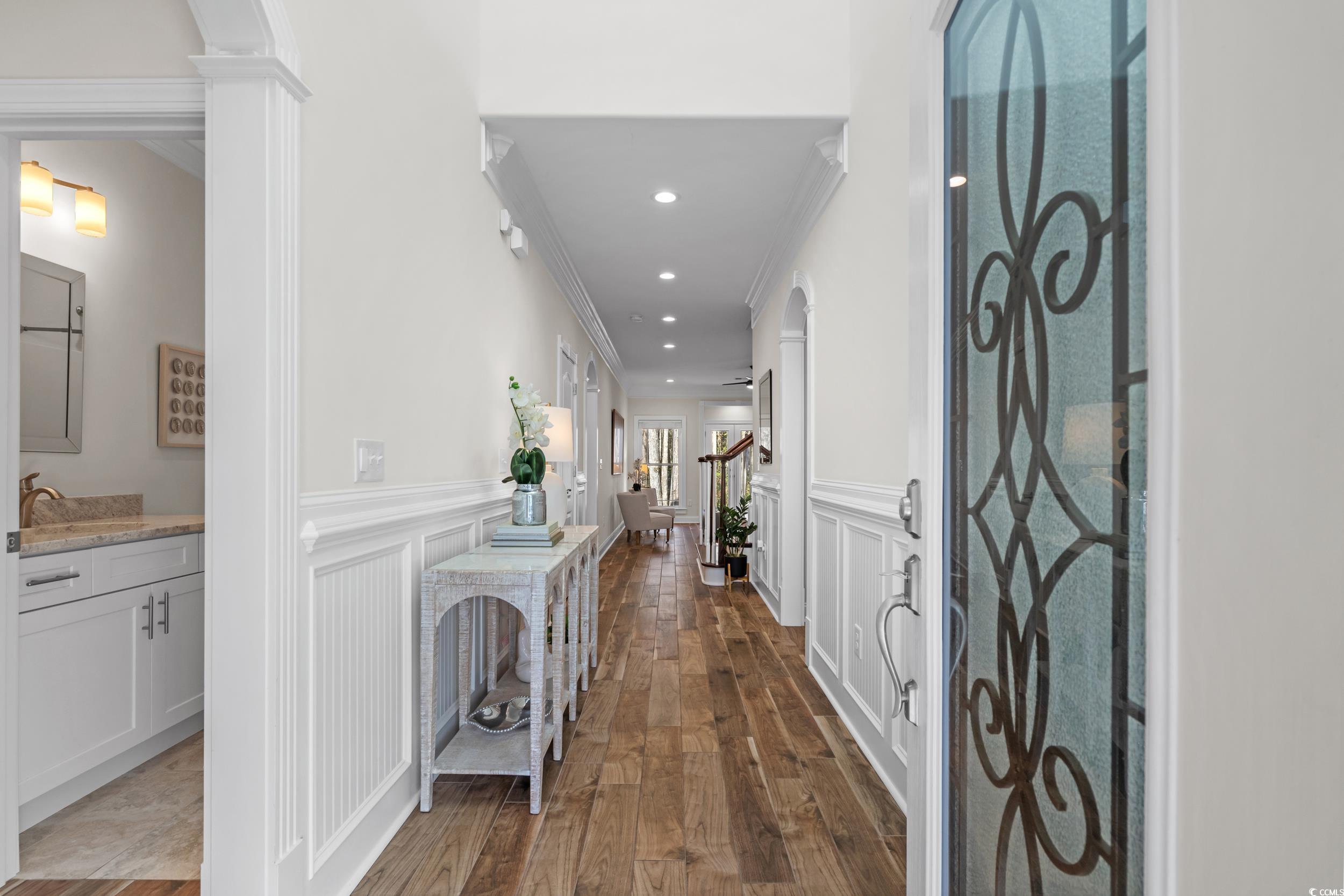 3021 Moss Bridge Lane Myrtle Beach, SC 29579 - Photo 4 of 40 Hallway featuring arched walkways, a decorative wall, crown molding, dark wood-style flooring, and wainscoting