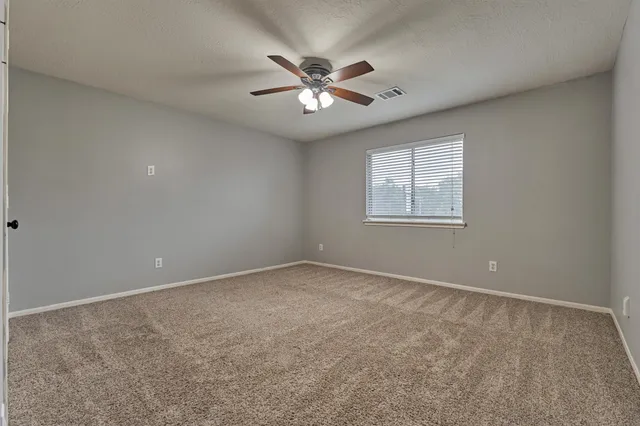an empty room with windows and ceiling fan