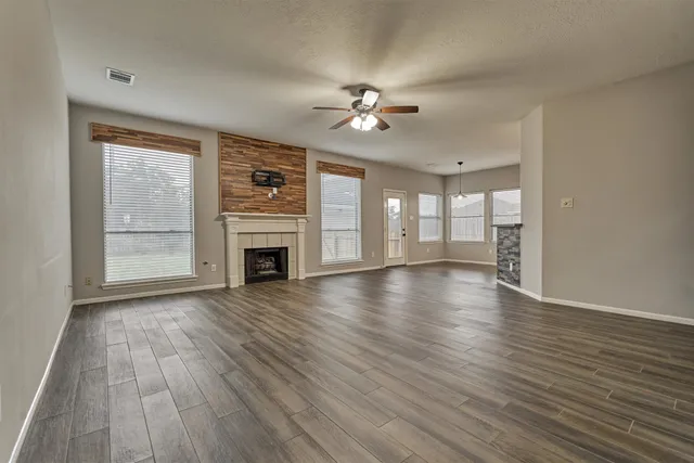 a view of a livingroom with wooden floor fireplace and a window