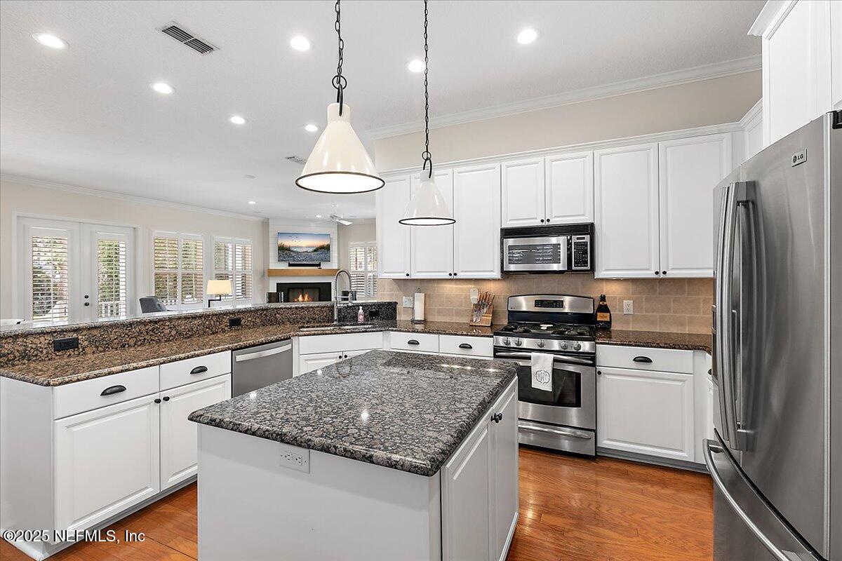 321 Fifth Street Atlantic Beach, FL 32233 - Photo 14 of 33 a kitchen with stainless steel appliances granite countertop a stove top oven a sink dishwasher a refrigerator and white cabinets with wooden floor