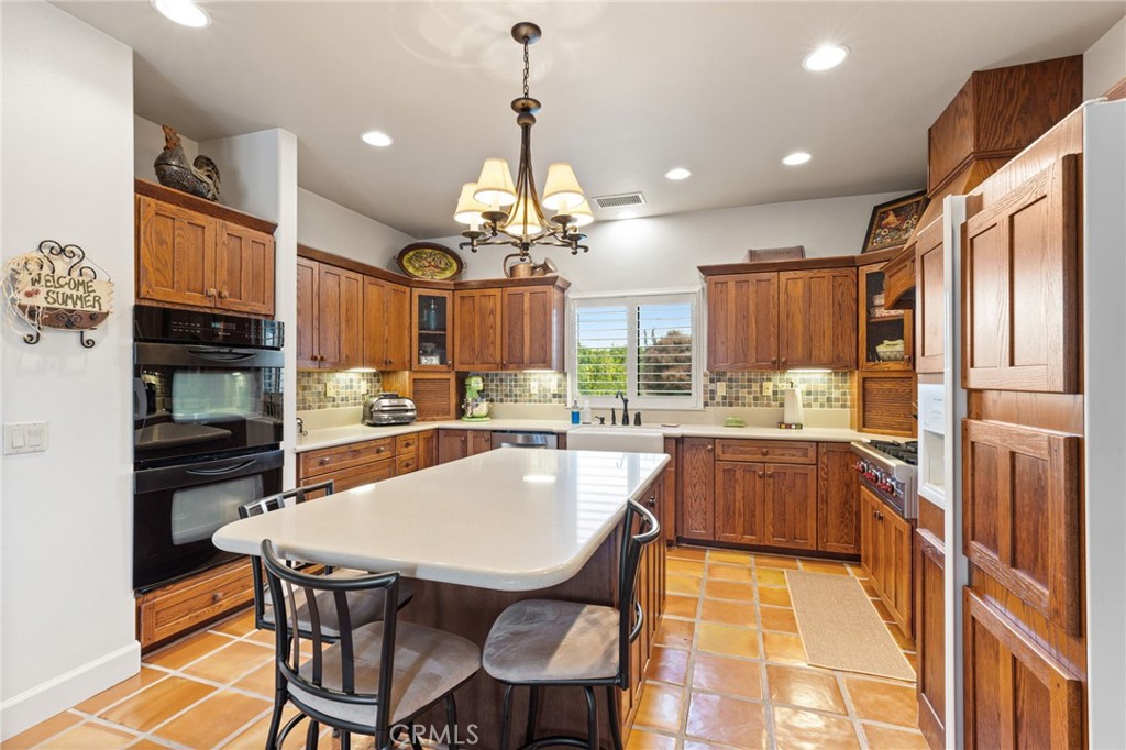 26487 Thacker Drive Hemet, CA 92544 - Photo 33 of 60 a kitchen with stainless steel appliances kitchen island granite countertop a table chairs and a refrigerator