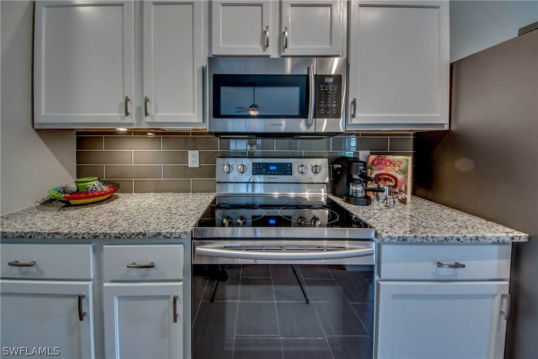 17520 Oriole Road Fort Myers, FL 33967 - Photo 6 of 25 a kitchen with granite countertop a stove top oven microwave and cabinets