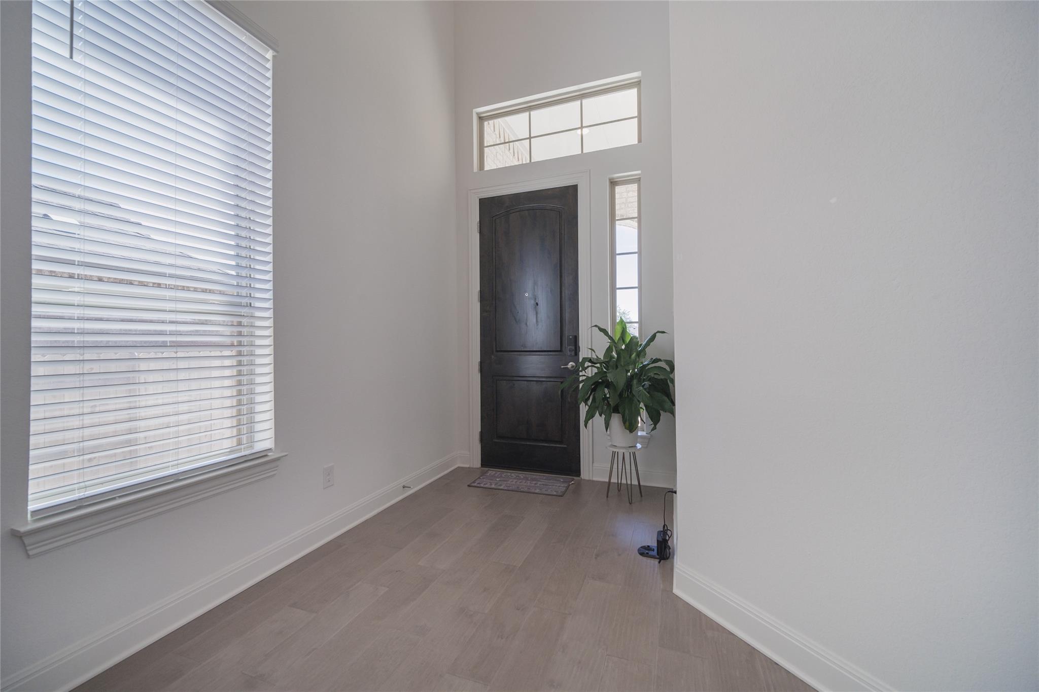 3049 Sage Ranch Drive Leander, TX 78641 - Photo 22 of 23 A dark wood entry door, bathed in natural light from the transom and side window, welcomes all.