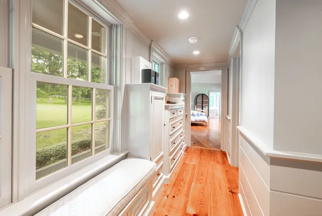 a view of a hallway with wooden floor and a bathroom