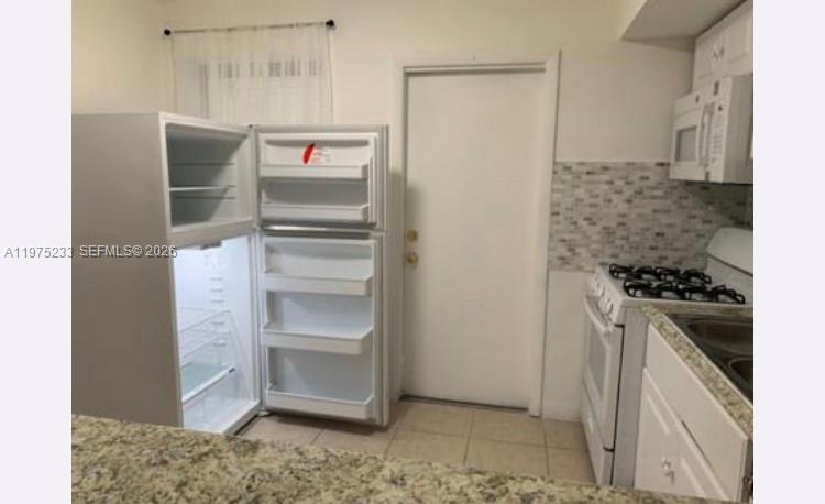 401 Southwest 8th Street, Unit A Hallandale Beach, FL 33009 - Photo 5 of 17 a kitchen with a refrigerator and a stove top oven