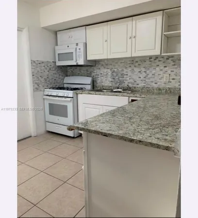 a kitchen with granite countertop white cabinets and white appliances