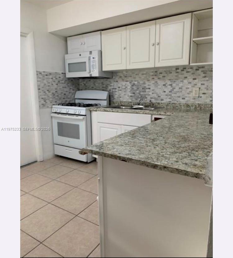 401 Southwest 8th Street, Unit A Hallandale Beach, FL 33009 - Photo 6 of 17 a kitchen with granite countertop white cabinets and white appliances