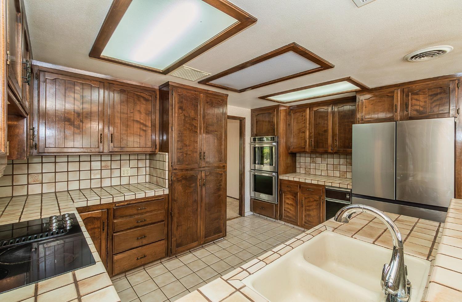 10574 Millerton Road Clovis, CA 93619 - Photo 13 of 36 a room with stainless steel appliances kitchen island granite countertop a refrigerator and a stove