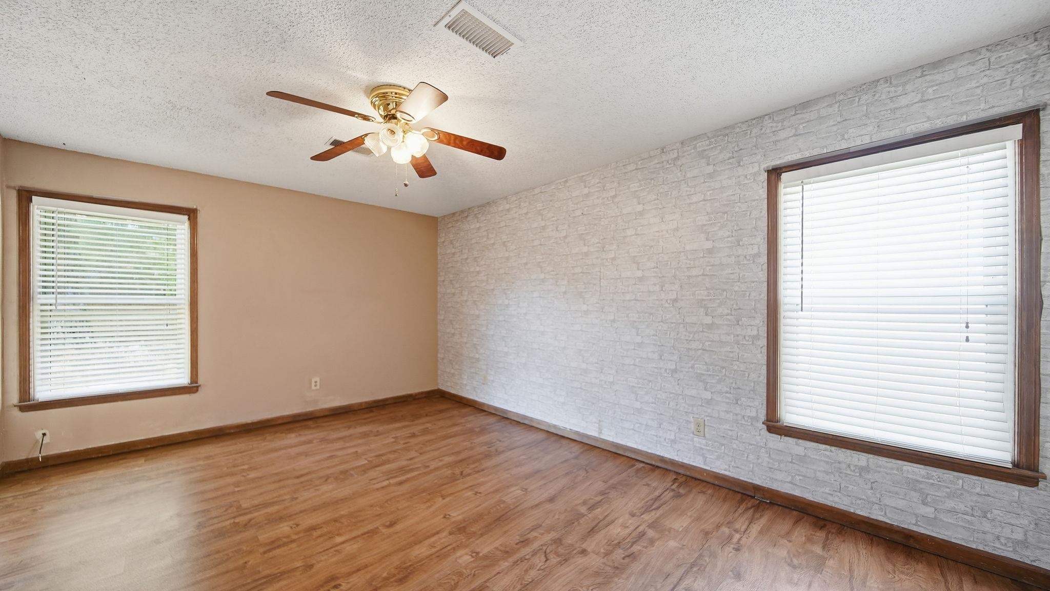 5069 Ross Road Memphis, TN 38141 - Photo 18 of 40 Unfurnished room featuring brick wall, light wood-style floors, a textured ceiling, and ceiling fan