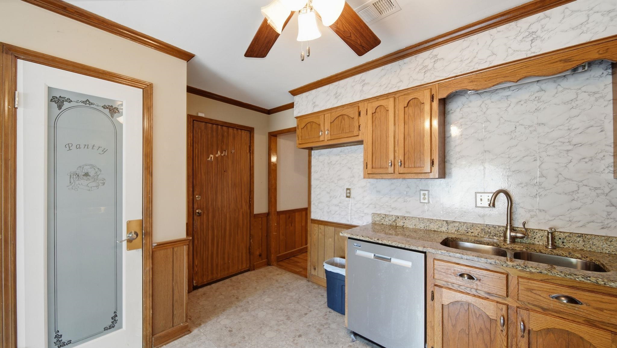 5069 Ross Road Memphis, TN 38141 - Photo 29 of 40 Kitchen with a wainscoted wall, light stone counters, stainless steel dishwasher, wood walls, and ornamental molding