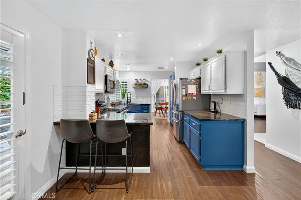 a kitchen with stainless steel appliances kitchen island granite countertop a table chairs and a refrigerator