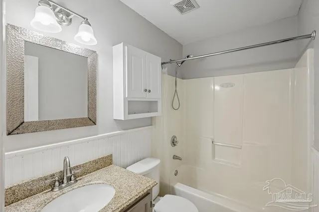 a bathroom with a granite countertop shower sink vanity mirror and toilet