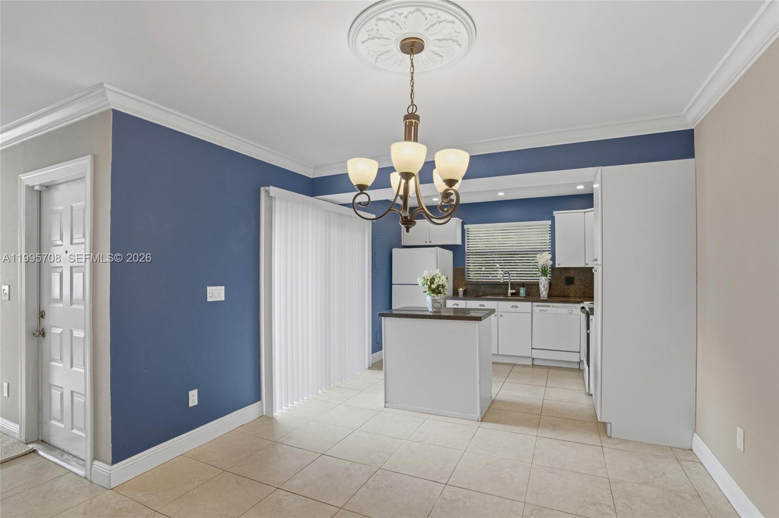 13993 Southwest 94th Cir Lane, Unit 1013 Miami, FL 33186 - Photo 11 of 36 a dining room with chandelier and kitchen view