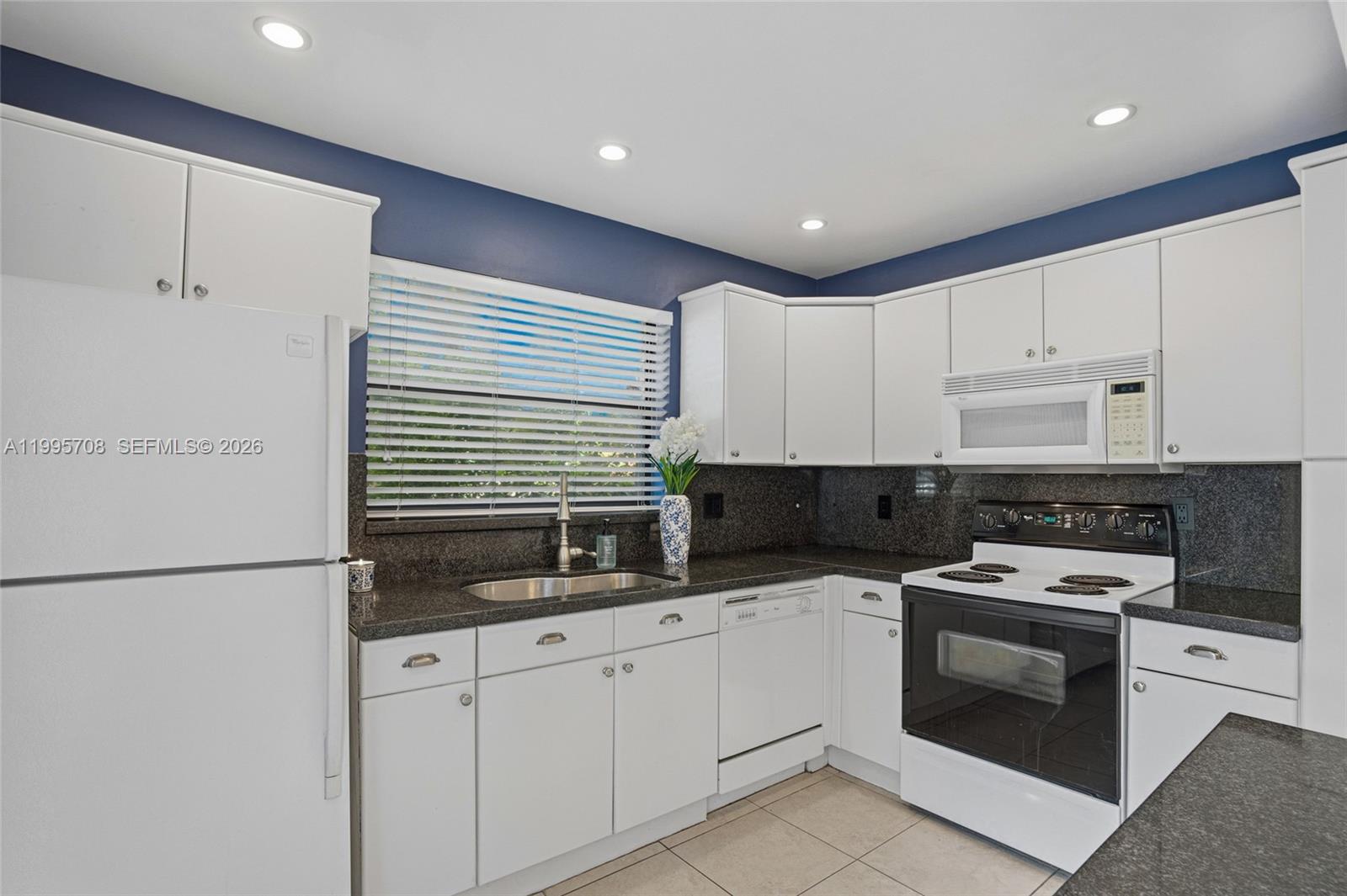 13993 Southwest 94th Cir Lane, Unit 1013 Miami, FL 33186 - Photo 14 of 36 a kitchen with granite countertop white cabinets and white appliances