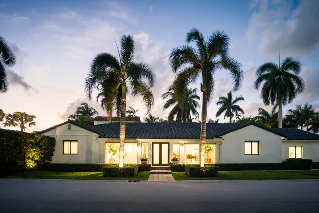 a view of a house with a yard and palm trees