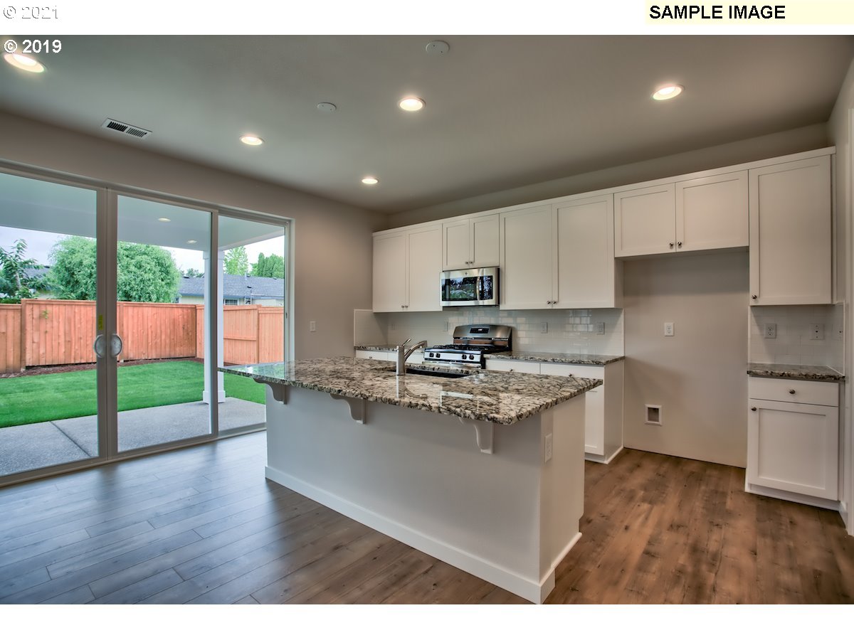 North Mccanta Way Ridgefield, WA 98642 - Photo 8 of 12 a kitchen with kitchen island a sink a stove a refrigerator and wooden cabinets