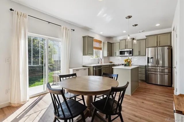 a kitchen with a dining table chairs and refrigerator