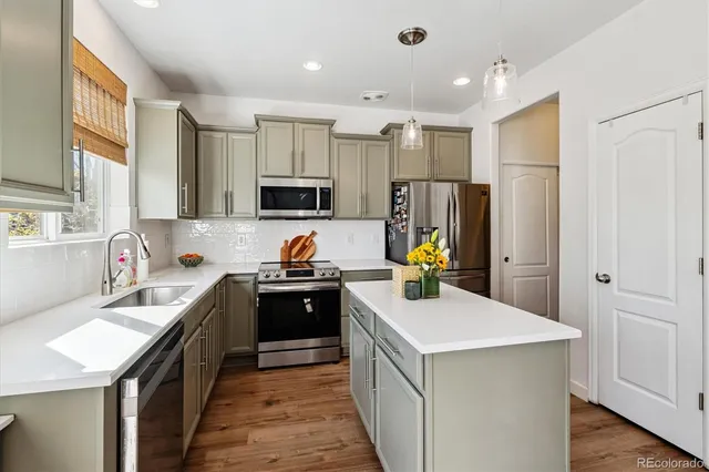 a kitchen with a stove a refrigerator a sink a oven with wooden cabinets and wooden floor