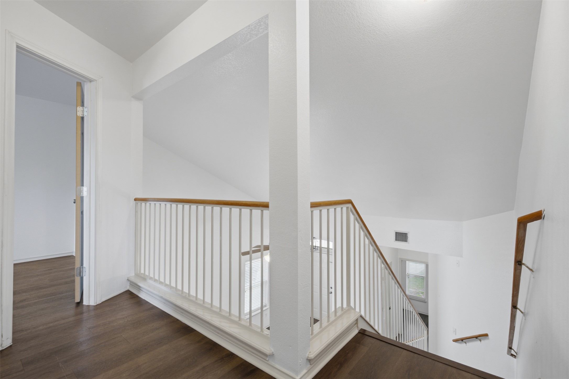 1416 Roxanne's Run Pflugerville, TX 78660 - Photo 21 of 35 A well-lit landing and staircase featuring rich wood flooring and crisp white railings lead to upper and lower levels.