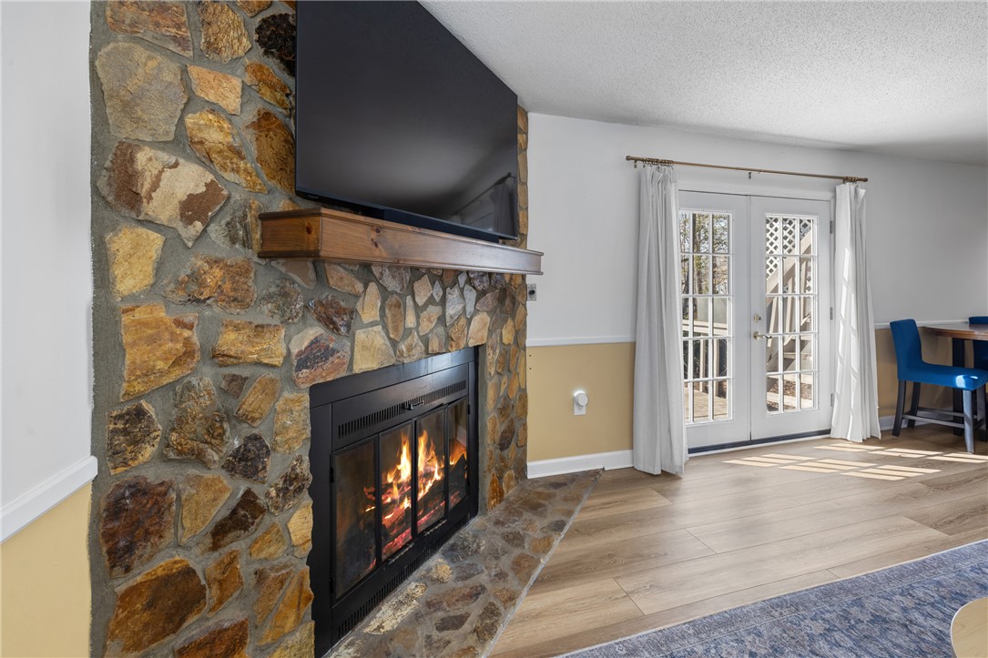 111 Shorecrest Drive Seneca, SC 29672 - Photo 26 of 35 A cozy living space features a stone fireplace with a rustic mantel and warm wood flooring.