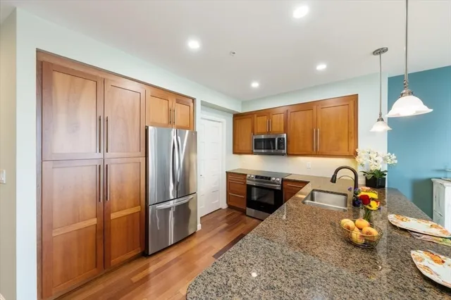 a kitchen with granite countertop a refrigerator stove and wooden floor