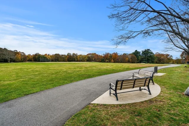 a view of a lake with a garden and a bench in the background