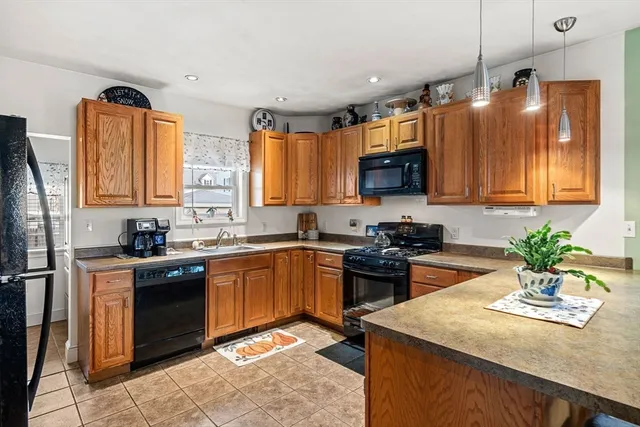 a kitchen with stainless steel appliances granite countertop a sink a stove a refrigerator cabinets and a window