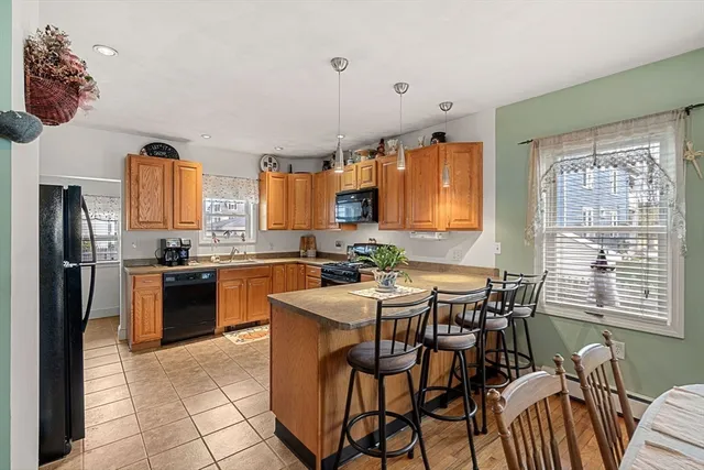 a kitchen with stainless steel appliances granite countertop a stove a sink a refrigerator dining table and chairs
