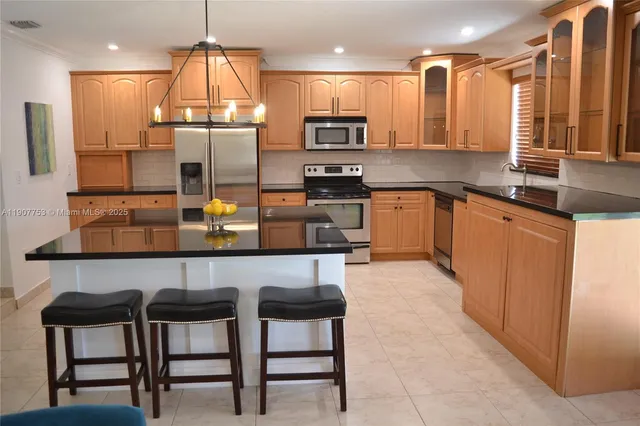 a kitchen with stainless steel appliances granite countertop a sink refrigerator and cabinets