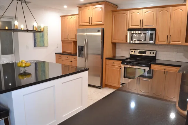 a kitchen with stainless steel appliances granite countertop a refrigerator a stove a sink and a microwave