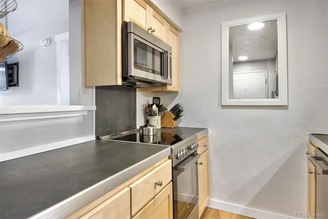 a kitchen with stainless steel appliances granite countertop a sink a stove and a microwave oven on the counter