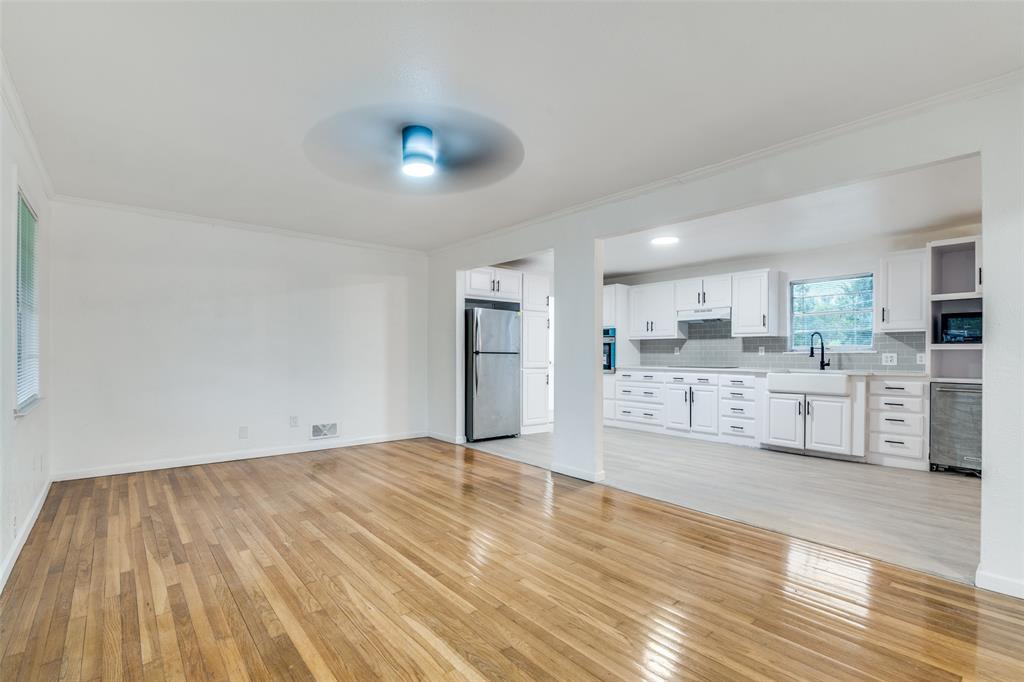 3308 Ranch Drive Garland, TX 75041 - Photo 11 of 25 a large white kitchen with kitchen island a sink dishwasher a stove and white cabinets with wooden floor