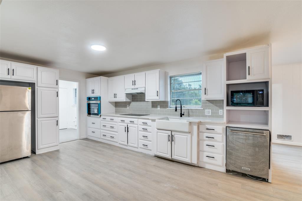 3308 Ranch Drive Garland, TX 75041 - Photo 12 of 25 a kitchen with white cabinets and stainless steel appliances