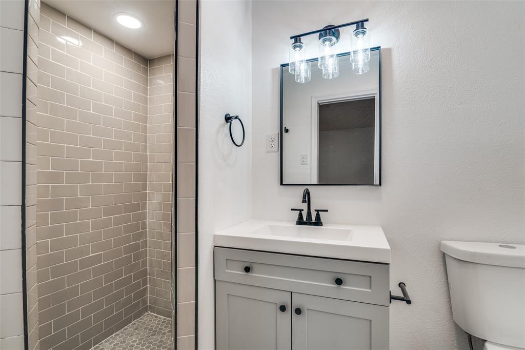 3308 Ranch Drive Garland, TX 75041 - Photo 18 of 25 a bathroom with a sink a mirror and a toilet