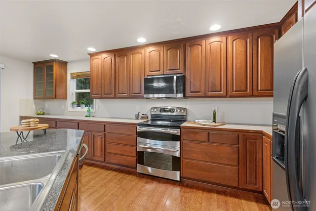 a kitchen with stainless steel appliances granite countertop a stove a sink and a microwave