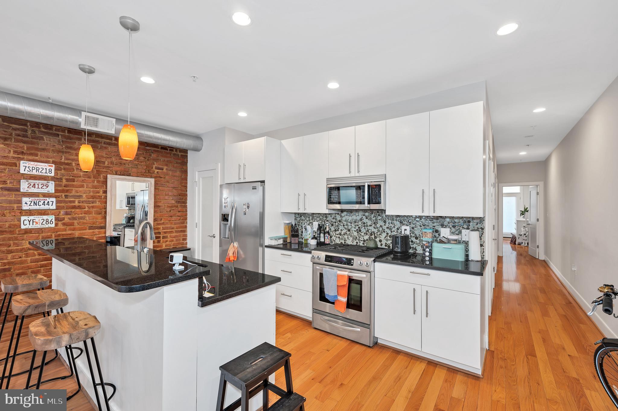 2444 Ontario Road Northwest, Unit 2 Washington, DC 20009 - Photo 8 of 29 a kitchen with stainless steel appliances kitchen island granite countertop a stove a sink a refrigerator and white cabinets with wooden floor
