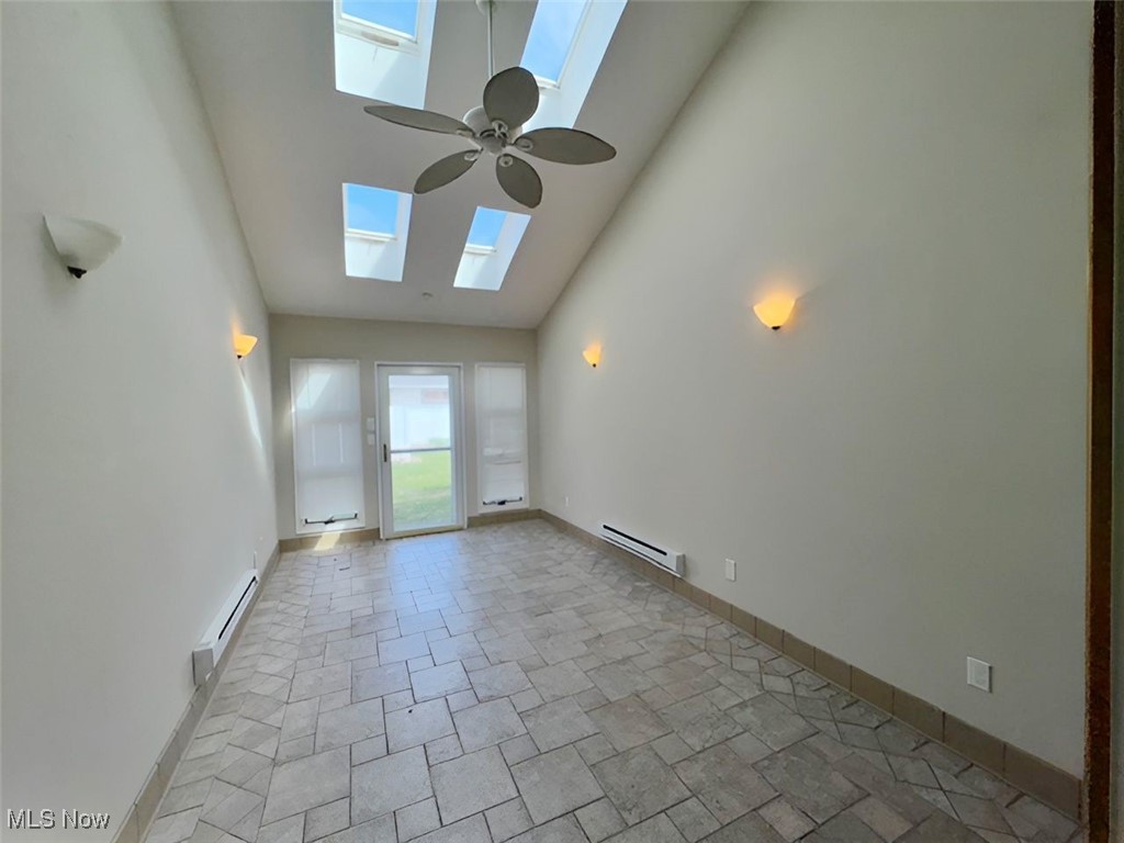 6224 Reynolds Road Mentor, OH 44060 - Photo 12 of 29 Empty room with a skylight, high vaulted ceiling, ceiling fan, baseboard heating, and stone finish flooring