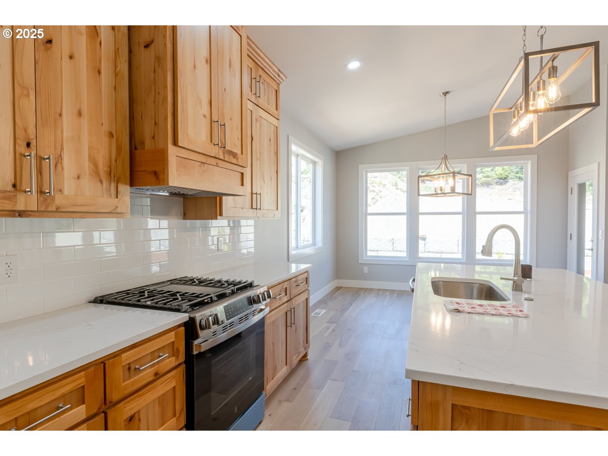 413 Meadows Drive Nehalem, OR 97131 - Photo 5 of 13 a kitchen with granite countertop a stove and a wooden cabinets