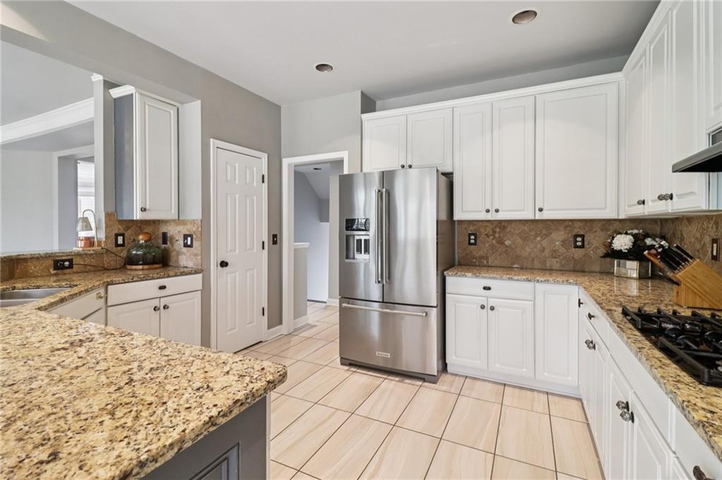5840 Masters Club Drive Suwanee, GA 30024 - Photo 24 of 72 a kitchen with granite countertop a refrigerator and a stove top oven