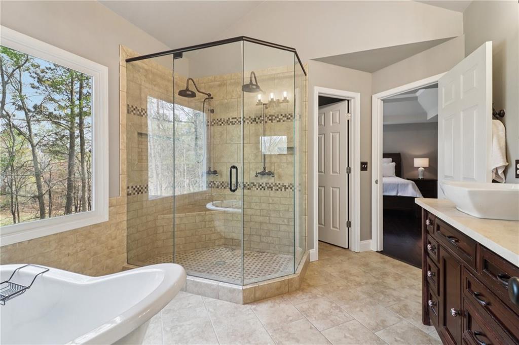 5840 Masters Club Drive Suwanee, GA 30024 - Photo 35 of 72 a bathroom with a tub a sink a mirror and a shower