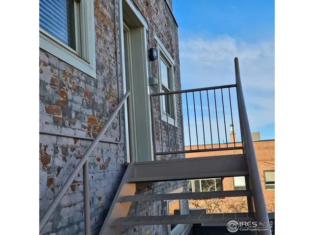 a view of a roof deck with table and chairs under an umbrella with wooden floor