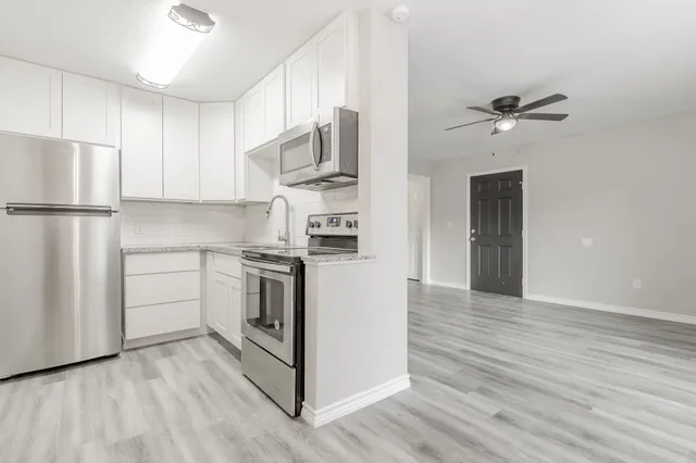 a kitchen with stainless steel appliances white cabinets and wooden floors